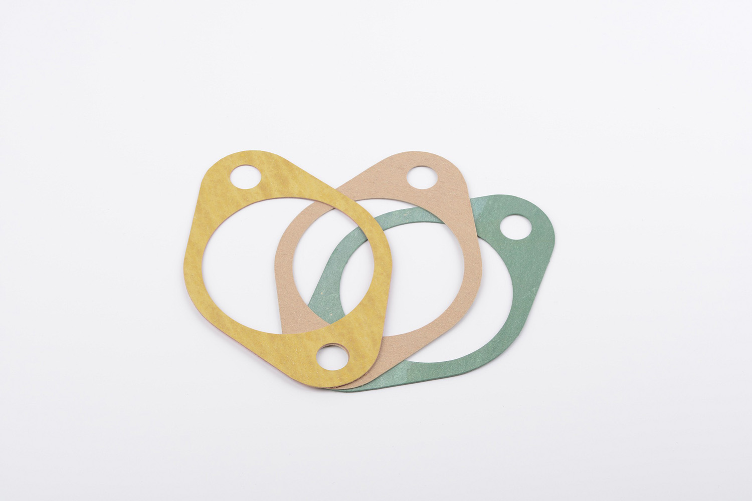 Drei unterschiedlich farbige (gelb, beige, grün), präzise gestanzte Stanzteile.