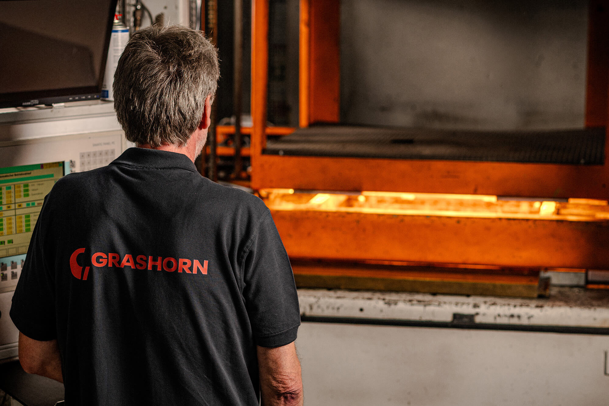 Ein Grashorn-Mitarbeiter überwacht den Thermoformprozess, bei dem eine Kunststoffplatte in einer großen Maschine erhitzt wird, um sie formbar zu machen.