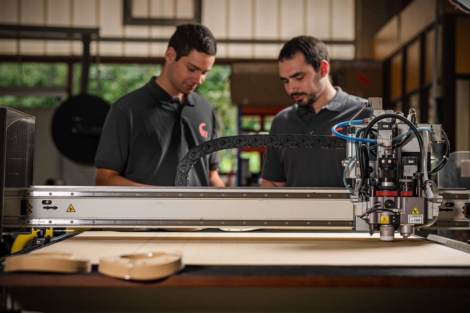 Zwei Mitarbeiter im Gespräch vor einer Schneidemaschine.