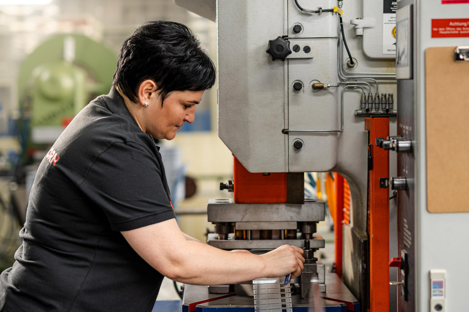 Eine Mitarbeiterin von Grashorn bedient einen Hochgeschwindigkeits-Stanzautomaten für die Fertigung technischer Stanzteile in Großserie.