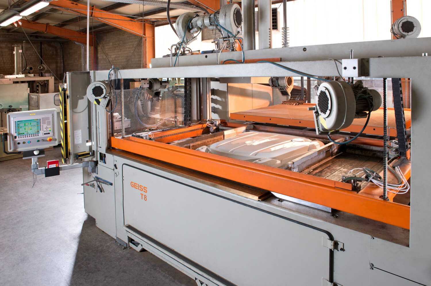 Eine Thermoformanlage mit einem fertig geformten weißen Kunststoffteil in der Form.