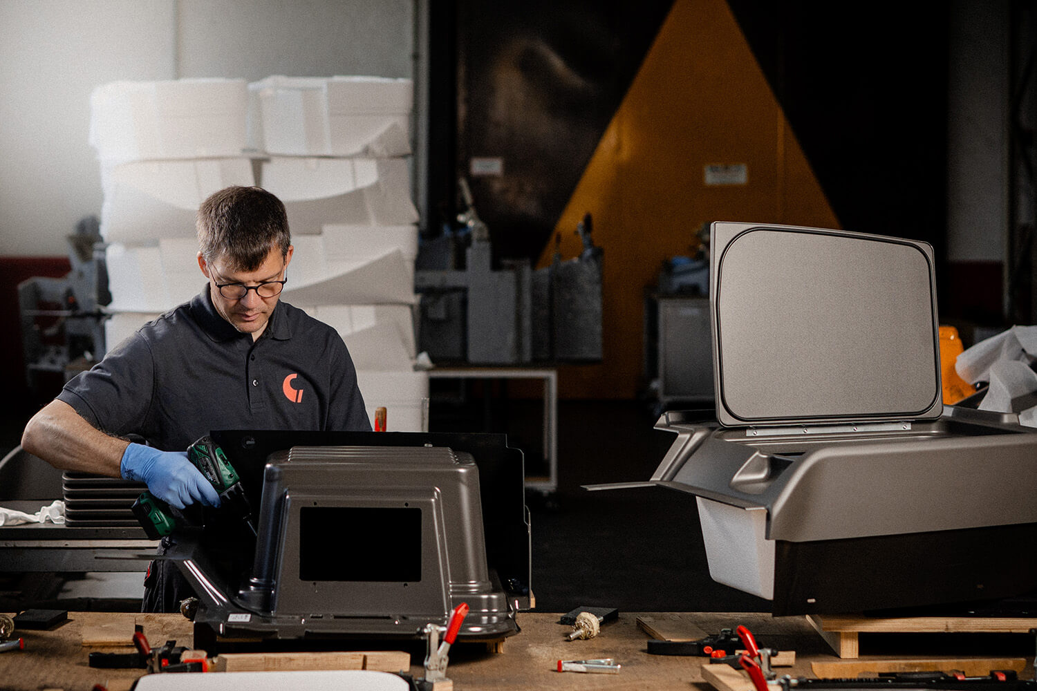 Ein Mitarbeiter montiert in der Fertigungshalle von Grashorn eine komplexe Baugruppe aus mehreren Kunststoff-Formteilen.